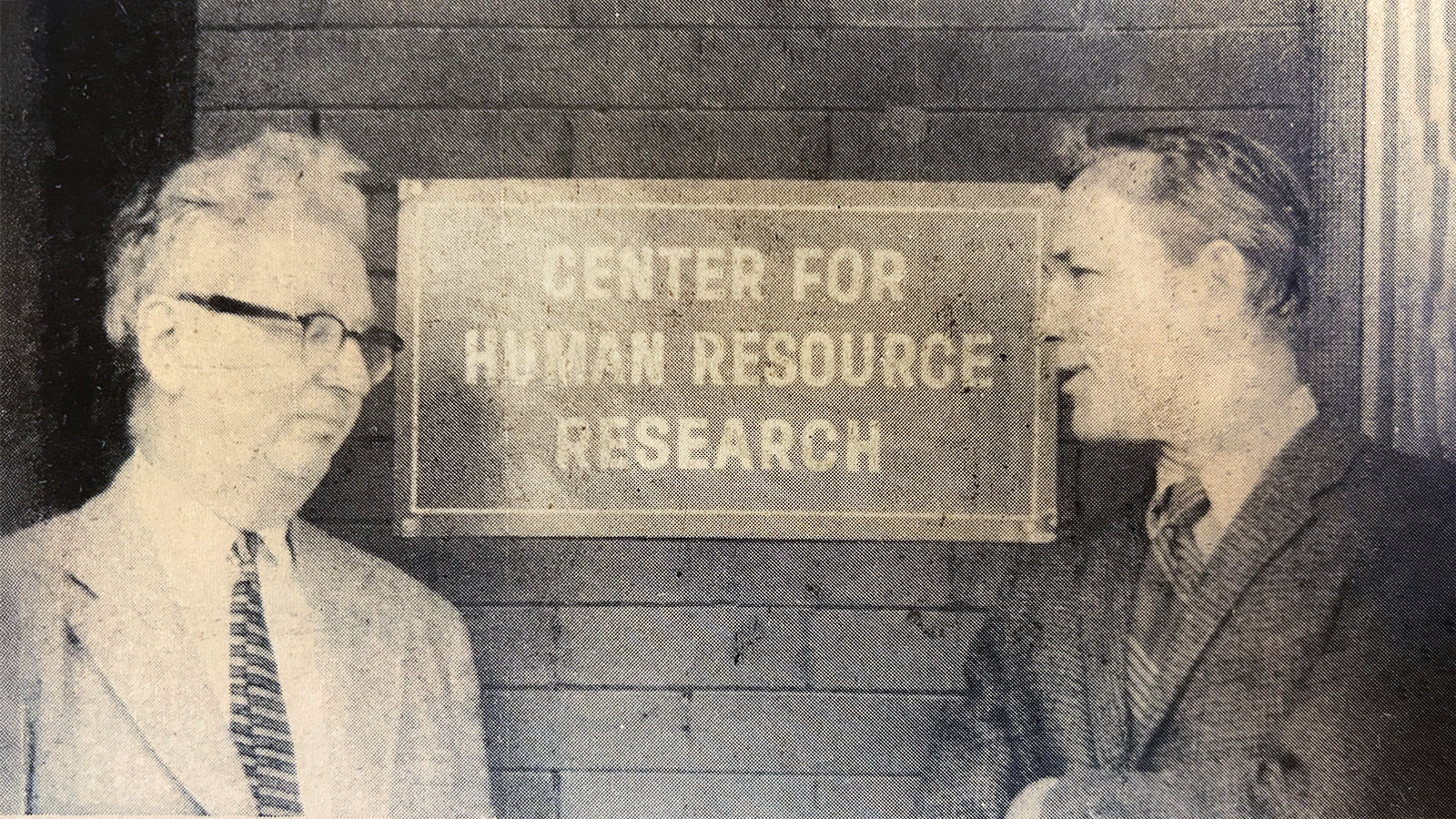 Historical newspaper clipping depicting two men talking in front of CHRR sign