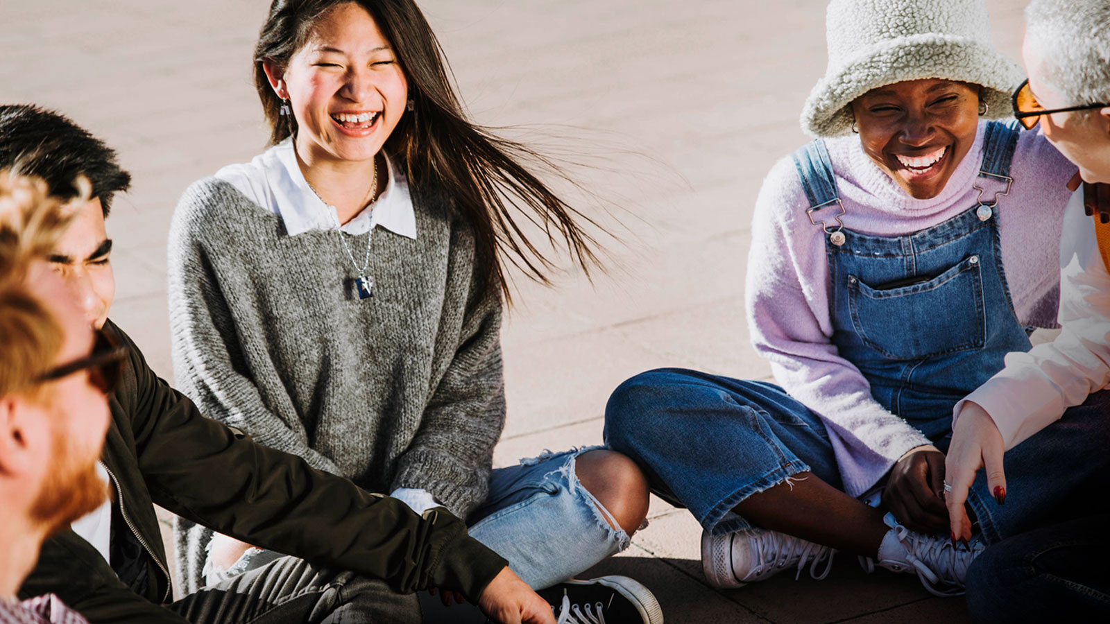 Teens sitting outside and interacting, laughing