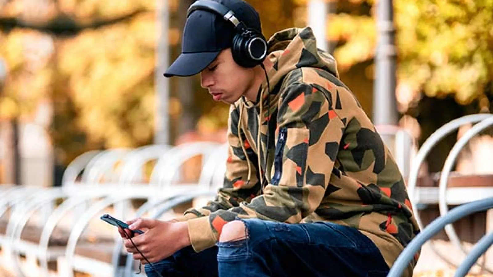 Teen sitting on bench looking at cellphone
