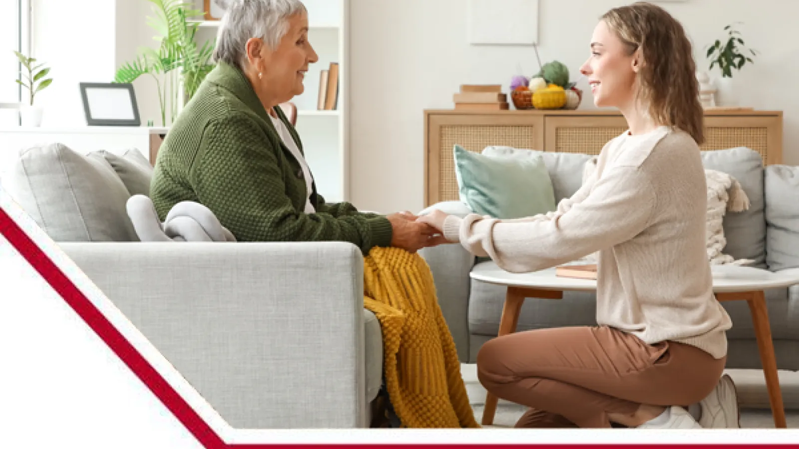 Woman in 30's crouching down and holding hands with woman in 70's who is sitting