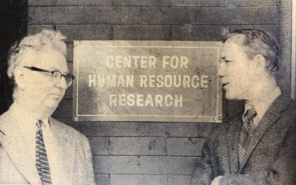 Historical newspaper clipping depicting two men talking in front of CHRR sign